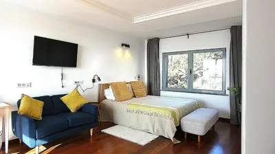 a bedroom with a bed and a couch and a window at Madeira Serenity Cottage in Funchal