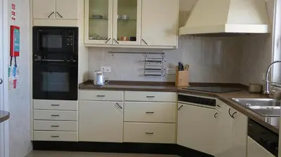 a kitchen with white cabinets and a black refrigerator at Madeira Serenity Cottage in Funchal