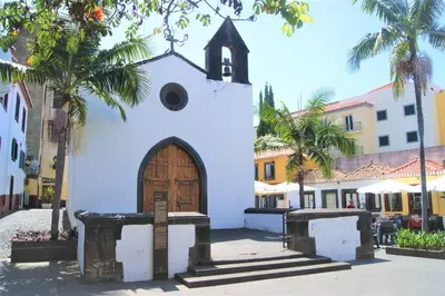 a church with a wooden door in a street at Casa da Avó Irene in Funchal