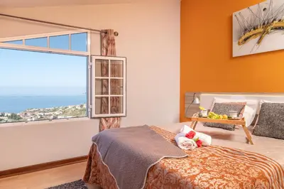 a bedroom with a bed and a large window at Casa Por Do Sol in Ponta do Sol