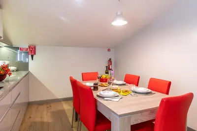 a dining room with a table and red chairs at Casa Por Do Sol in Ponta do Sol