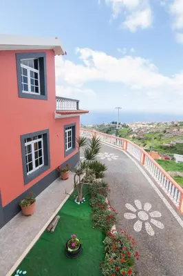 a house with a balcony with a green lawn at Casa Por Do Sol in Ponta do Sol