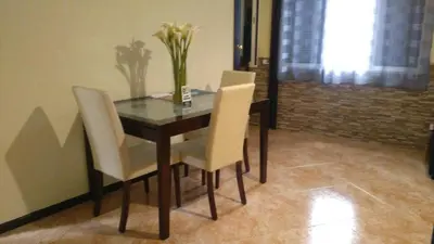 a dining room table with white chairs and a vase of flowers at House Joel & Sónia in Funchal