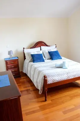 a bedroom with a bed with blue pillows and a table at Casa Simão in Calheta