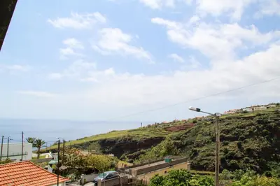a view of a hill with houses and the ocean at Casa Simão in Calheta