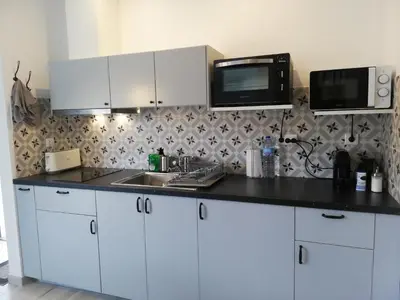 a kitchen with white cabinets and a sink and a microwave at Lopes Apartment - Belch1952 in Lagos
