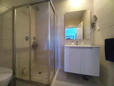 a bathroom with a shower and a sink and a mirror at Lopes Apartment - Belch1952 in Lagos