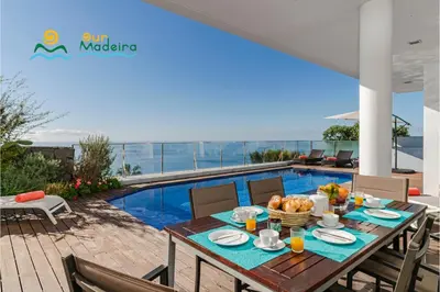 a table with food on it on a patio with a pool at OurMadeira - Fonte do Mar 1 in Caniço