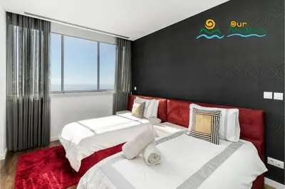 two beds in a bedroom with a red headboard at OurMadeira - Fonte do Mar 1 in Caniço