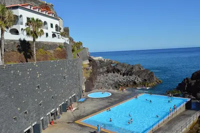 a swimming pool next to the ocean and a building at Apartment in Câmara de Lobos in Câmara de Lobos