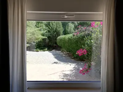 a window with a view of a garden with pink flowers at Manuel Apartment - Belch1952 in Lagos