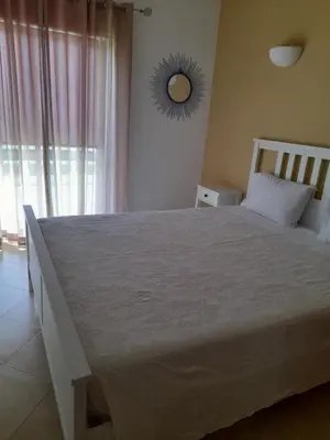 a bedroom with a large white bed with a window at Apartamento Maria in Lagos