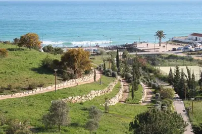 a field with a fence and a road next to the ocean at Apartamento Maria in Lagos