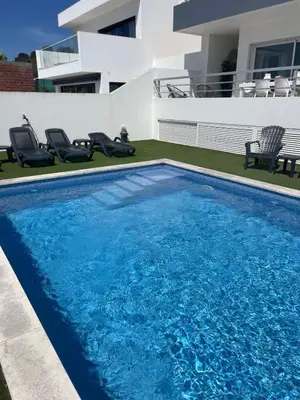 a swimming pool in front of a house at DuMar Beachouse in Salema