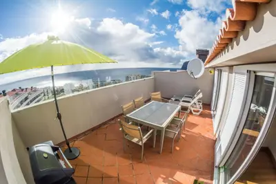 a balcony with a table and chairs and an umbrella at PERFECT DUPLEX PISCINE Zone VIP Funchal in Funchal
