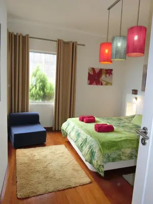 a bedroom with a bed and a chair and a window at Casa Marias in Calheta