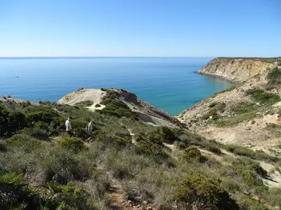 two people walking on a hill near the ocean at Casa Afonso Henriques in Burgau