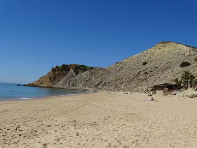 a beach with people on the sand and a mountain at Casa Afonso Henriques in Burgau