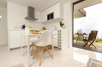 a white kitchen with a white table and chairs at BHF Residences Lotus in Calheta
