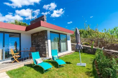 a house with two chairs and an umbrella in the yard at BHF Residences Lotus in Calheta