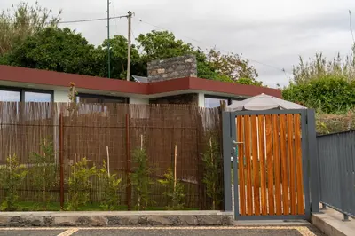 a fence with a wooden gate in front of a house at BHF Residences Lotus in Calheta