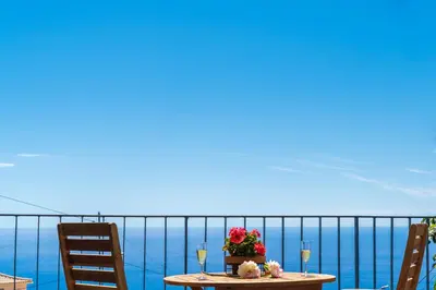 a table with flowers and wine glasses on a balcony at BHF Residences Ying Yang in Calheta