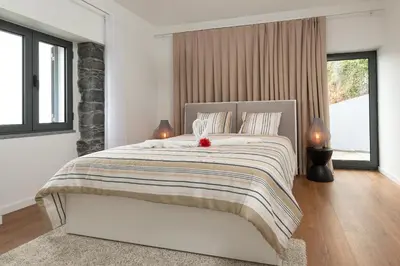 a white bedroom with a large bed with two lamps at BHF Residences Ying Yang in Calheta