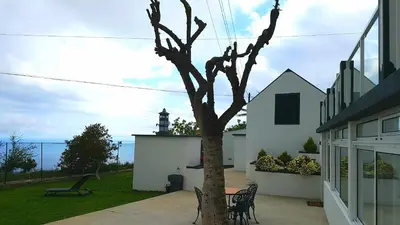 a tree in the yard of a house with a lighthouse at La Casa de la Abuela in Ponta do Sol