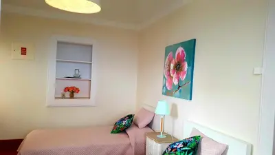 a bedroom with a pink bed and a flower painting on the wall at La Casa de la Abuela in Ponta do Sol