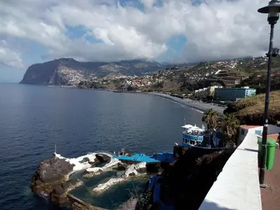a boat in a body of water with a beach at Apartamentos América - Blue Sea II in Funchal