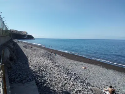 a beach with people on it and the ocean at Apartamentos América - Blue Sea II in Funchal