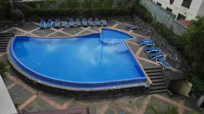 an overhead view of a large blue swimming pool with lounge chairs at Jasmineiro - Palms Palace Apartment in Funchal