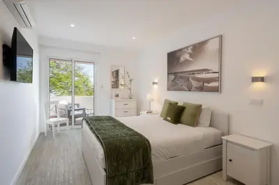 a white bedroom with a bed and a desk at Lido II by An Island Apart in Funchal