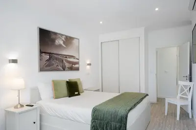 a white bedroom with a bed with a green blanket at Lido II by An Island Apart in Funchal