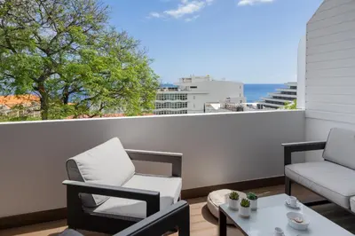 a patio with two chairs and a table on a balcony at Lido II by An Island Apart in Funchal