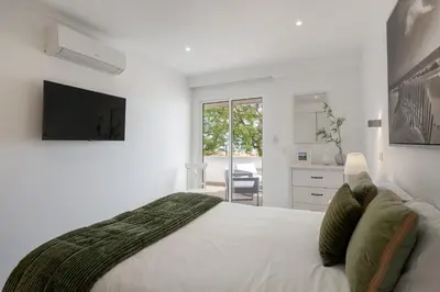 a white bedroom with a large bed and a television at Lido II by An Island Apart in Funchal