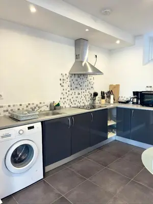 a kitchen with a table and a white refrigerator at O Cantinho do Zé in Funchal