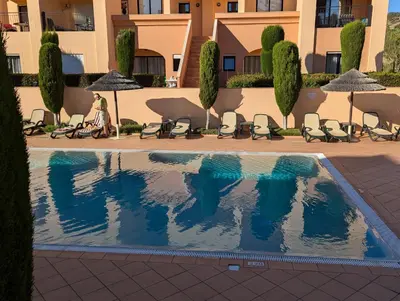 a woman sitting in a chair next to a swimming pool at Luxury 3-bedroom apartment at high-end Praia da Luz in Luz