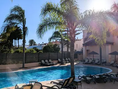 a swimming pool with chaise lounge chairs and palm trees at Luxury 3-bedroom apartment at high-end Praia da Luz in Luz