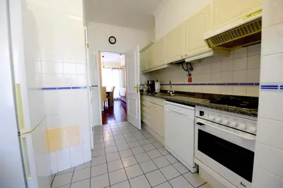 a kitchen with white cabinets and a white tile floor at Sol & Mar Camara de Lobos in Câmara de Lobos