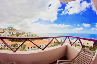 a balcony with a chair and a view of the ocean at Sol & Mar Camara de Lobos in Câmara de Lobos