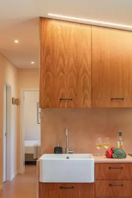 a kitchen with a white sink and wooden cabinets at Casas do Lanço by An Island Apart in São Vicente