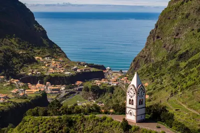 a church on a hill next to the ocean at Casas do Lanço by An Island Apart in São Vicente