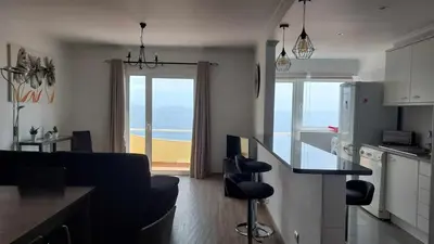 a kitchen and living room with a view of the beach at Portinho II-Modern apt with balcony facing the sea in Caniço