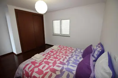a bedroom with a bed with a pink and purple comforter at Portinho II-Modern apt with balcony facing the sea in Caniço