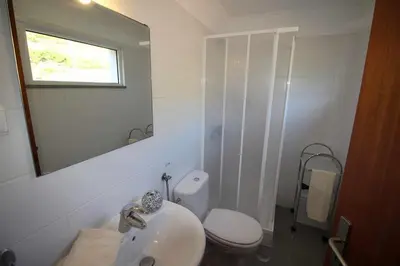 a bathroom with a sink and a toilet and a mirror at Portinho II-Modern apt with balcony facing the sea in Caniço