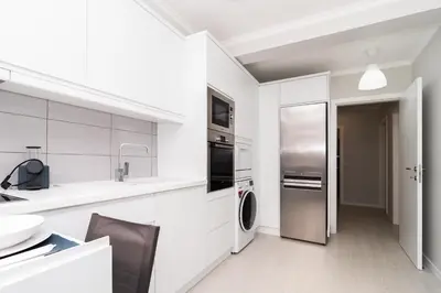 a kitchen with white cabinets and a stainless steel refrigerator at Villa Ponta do Sol Apartment in Ponta do Sol