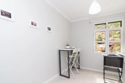 a white room with a table and two windows at Villa Ponta do Sol Apartment in Ponta do Sol
