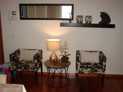 a living room with two chairs and a table with a lamp at Garajau Elite in Caniço