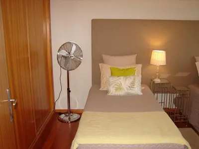 a bedroom with a large bed with a fan at Garajau Elite in Caniço